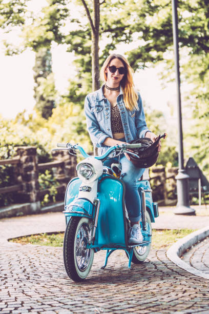 istock Young Smiling Woman and Her Old-fashioned Motor Scooter 1003127528