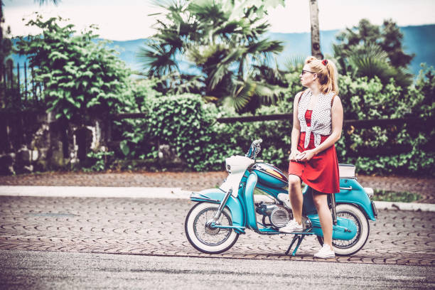 istock Young Woman Leaning on Her Motor Scooter and Looking Around 1003129640
