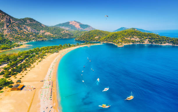 Amazing aerial view of Blue Lagoon in Oludeniz, Turkey. Summer landscape with sea spit, boats and yachts, green trees, azure water, sandy beach in sunny day. Travel. Top view of national park. Nature stock photo