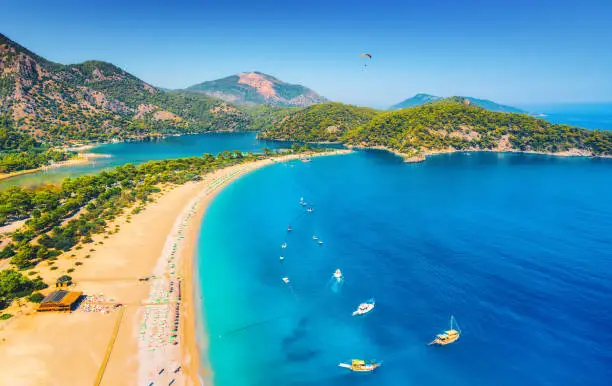 Photo of Amazing aerial view of Blue Lagoon in Oludeniz, Turkey. Summer landscape with sea spit, boats and yachts, green trees, azure water, sandy beach in sunny day. Travel. Top view of national park. Nature
