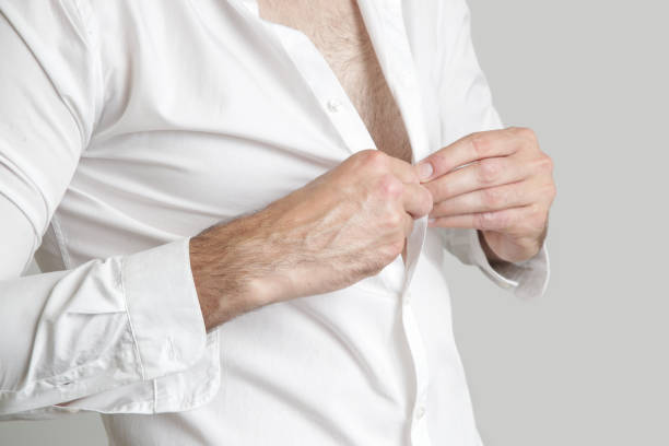 istock Handsome young man buttoning his white shirt 1003157416