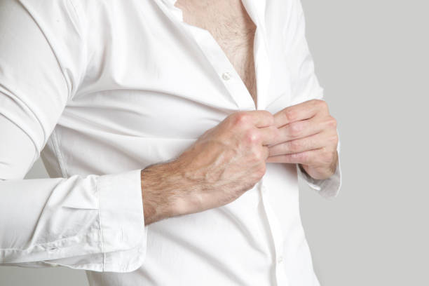 istock Handsome young man buttoning his white shirt 1003157460