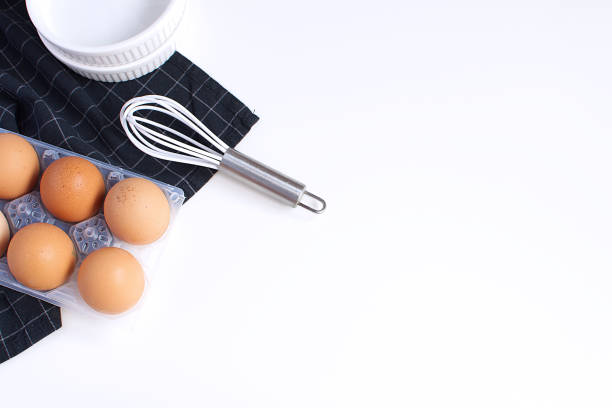istock Raw Eggs Whisk Baking mold and checkered black napkin Minimal Picture White Background Kitchen Supplement Copy Space Preparation Cooking Baking Kitchen Table Top view 1003162982