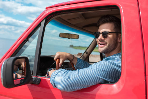 istock handsome smiling man in sunglasses driving car during road trip 1003166200
