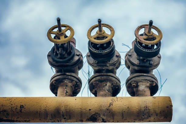 istock Three old pipe with valve, crane mechanism on sky background, vintage 1003172332