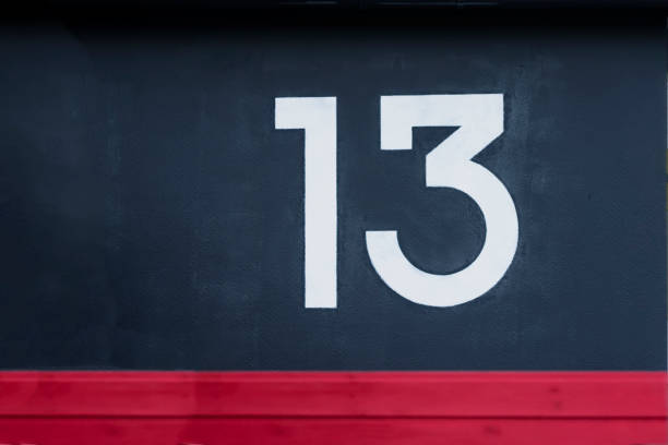 istock Written number thirteen on the blue red concrete wall 1003172576