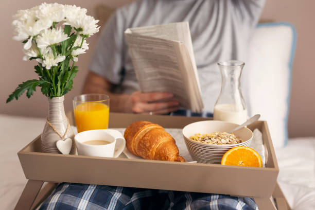 istock Man reading newspapers and having breakfast in bed 1003172652