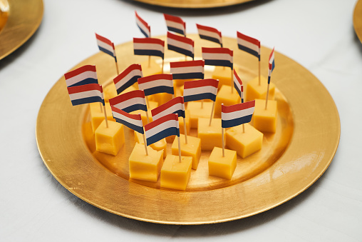 Dutch cheese cubes with flags. Gouda cheese snack with a dutch flag on a white table background, close-up