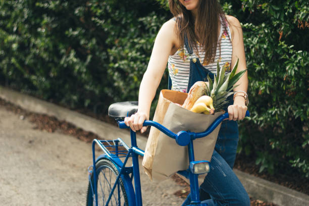 バスケットに食料品を持つ自転車に乗っている女性 - bicycle shop ストックフォトと画像