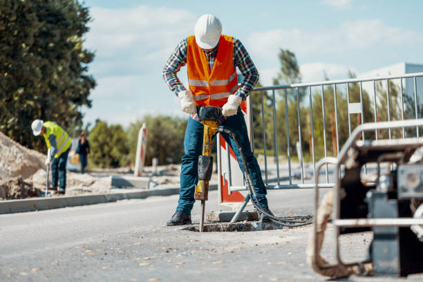 Worker in reflective vest with drill repairing street during roadworks Worker in reflective vest with drill repairing street during roadworks road construction photos stock pictures, royalty-free photos & images