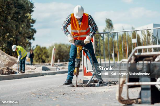 Worker In Reflective Vest With Drill Repairing Street During Roadworks Stock Photo - Download Image Now