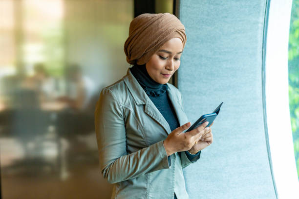 istock Muslim Business Woman Using a Mobile Phone in a Modern Office 1003215722