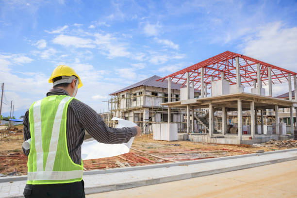 istock Professional engineer architect worker with protective helmet and blueprints paper at house building construction site 1003228294