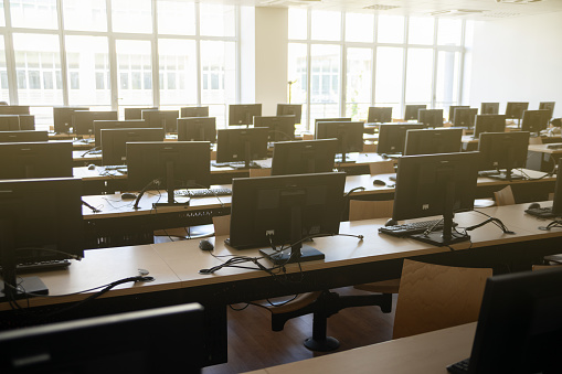 A medium shot of an IT classroom filled with desks, chairs and PC's in a secondary school in the North East of England.