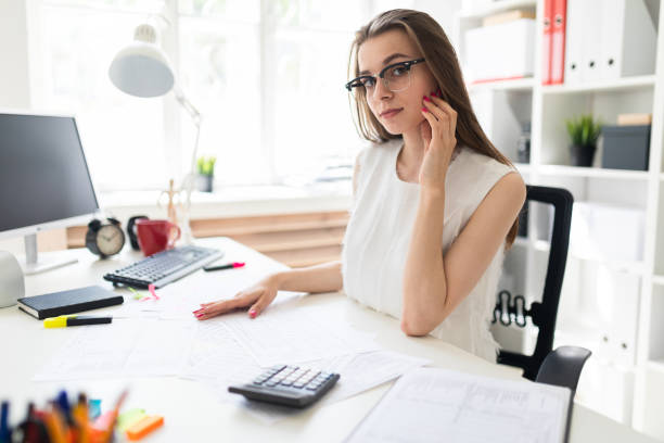 istock Young girl in the office sits at the table. On the table are documents. 1003236034