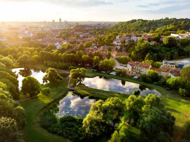 Aerial view of Vilnius cityscape shot from Subaciaus viewpoint on sunset. Clouds reflecting in three little ponds of Lithuania capital's city park.