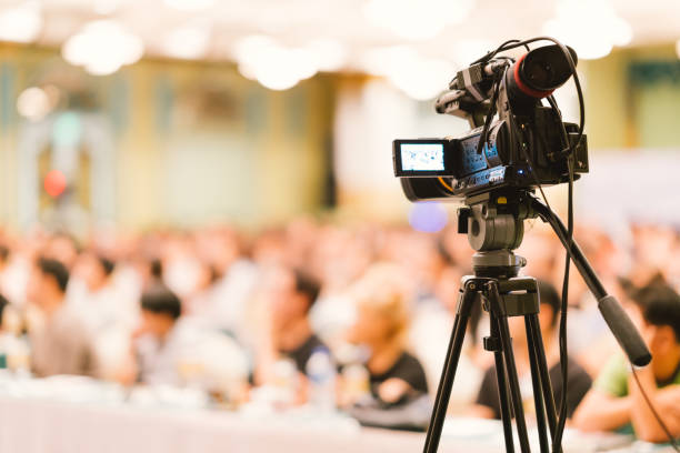 Video camera set record audience in conference hall seminar event. Company meeting, exhibition convention center, corporate announcement, public speaker, journalism industry, or news reporter concept stock photo