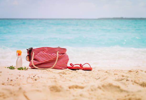 istock Beach bag, flip-flop and suncream on beach 1003248824