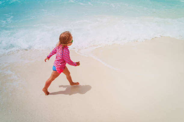 istock little girl run play with waves on the beach 1003249004