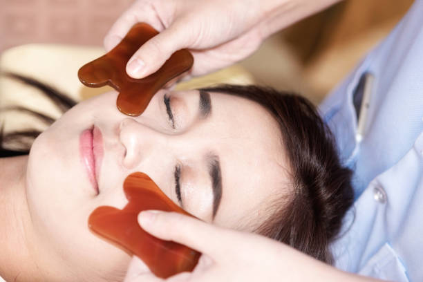 young woman undergoing acupuncture treatment by jade at the health spa message; cupping treatment to beautiful woman in beauty Spa. stock photo