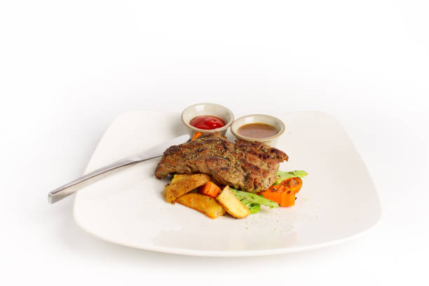 istock Beef steak grilled with  black peper gravy, mixed vegetables, potatoes, ketchup on white background 1003299858