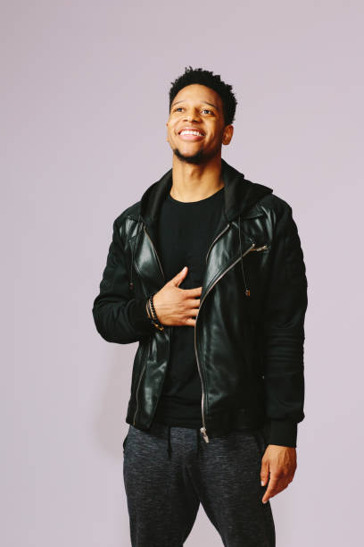 istock Cool smiling young man in black leather jacket and hand on chest 1003312346