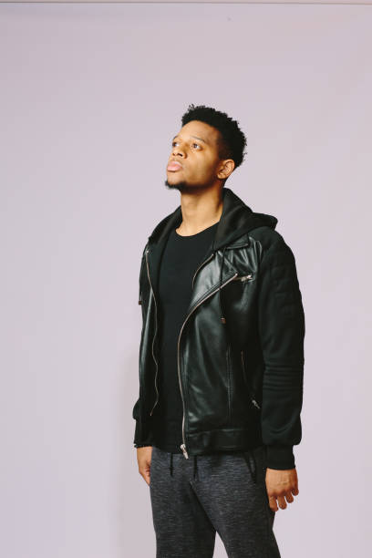 istock Vertical portrait of a standing young man in black looking up 1003312384