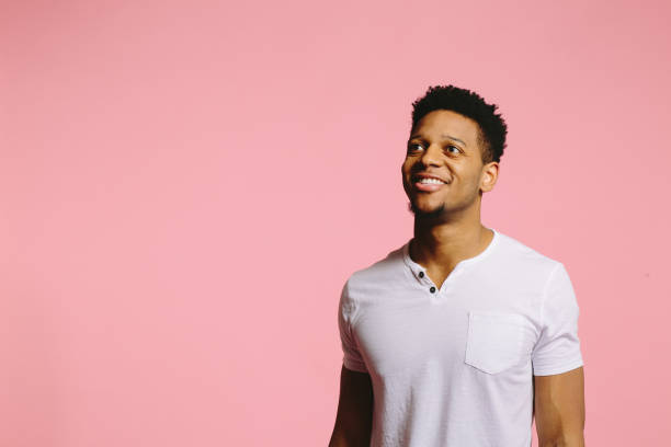 istock Happy young man smiling and looking up and to side, on pink 1003312476