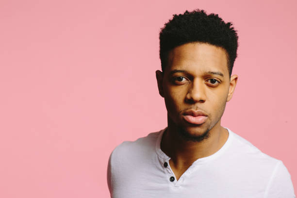 istock Serious and focused young man in white shirt looking at camera, on pink 1003312498
