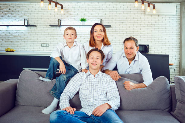 istock Happy family smiling sitting on sofa in room 1003319104