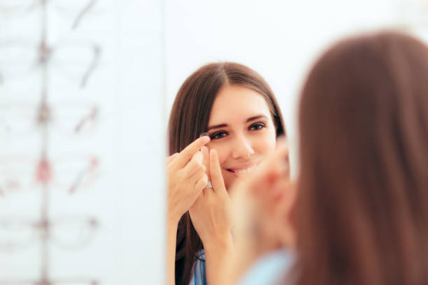 Girl Trying on Medical Contact Lenses in the Mirror Girl Trying on Medical Contact Lenses in the Mirror inserting stock pictures, royalty-free photos & images