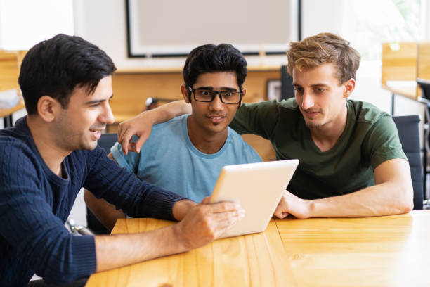 istock Smiling student showing tablet screen to surprised friends 1003325816