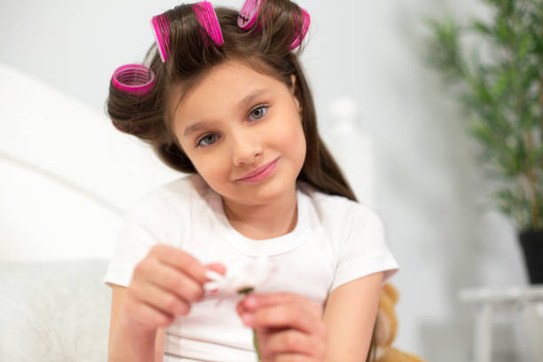 istock Young girl sitting on her bed with flower 1003326300