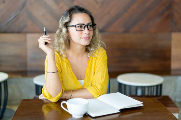 istock Pretty curly young woman writing notes for startup project 1003332530