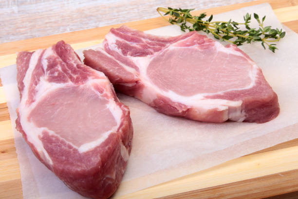 istock Raw pork chops, spices and rosemary on cutting board. Ready for cooking. 1003335438