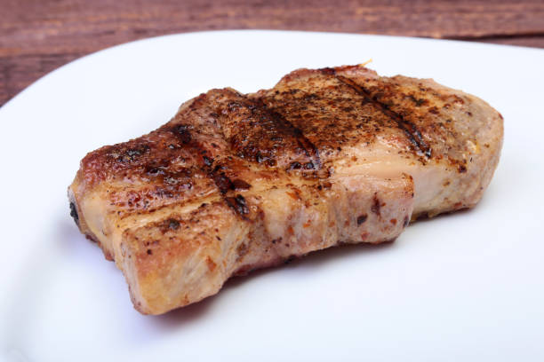 istock grilled pork chop on plate on wooden board 1003335618