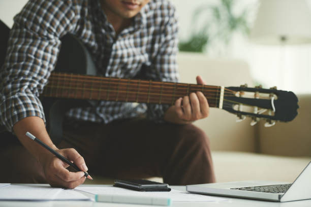 Composing music Cropped image of composer playing guitar and taking notes composer photos stock pictures, royalty-free photos & images