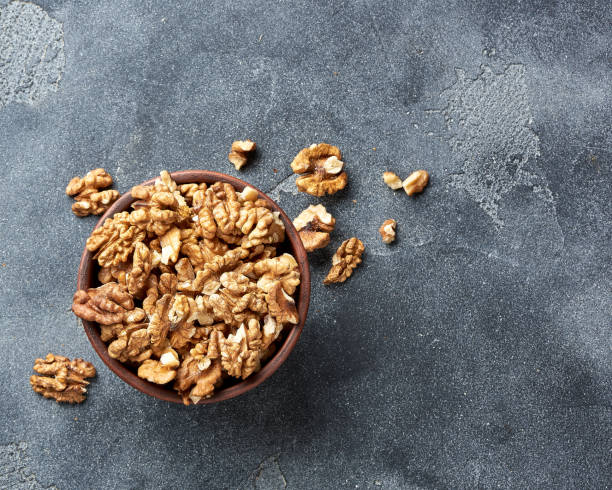 istock Walnut kernels in a bowl on gray background. Place for text. Top view 1003339674