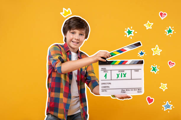 istock Cheerful boy holding a clapstick and shooting a film 1003358308