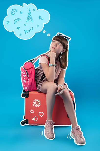 istock Dreamy girl thinking about Paris while sitting on her luggage 1003361742