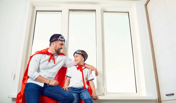 padre e figlio alla finestra della stanza - action family photograph fathers day foto e immagini stock