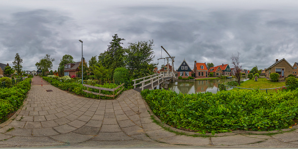 360 degrees spherical panoramic shot of a traditional Dutch village with old houses, wooden bridge and canal