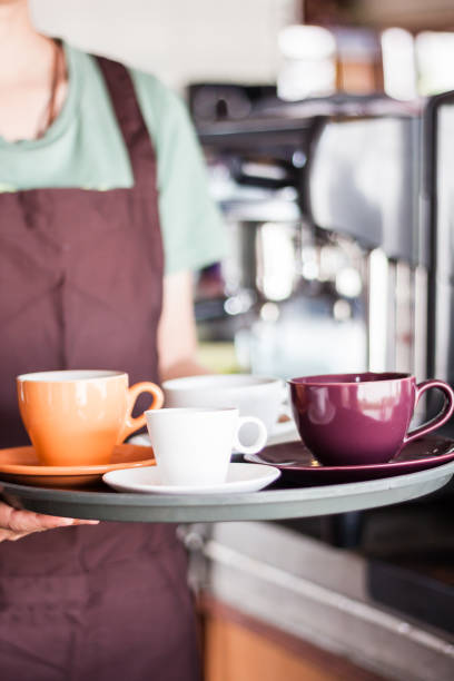 istock Midsection Of Waitress Holding Coffee Cups In Tray At Restaurant 1003385194