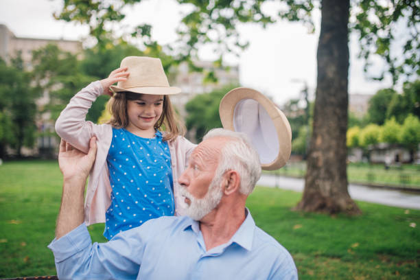 istock Old man holding granddaughter by the hand while she holds summer hats 1003385570