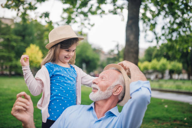 istock Beautiful young girl putting hat on grandpa's head 1003385836
