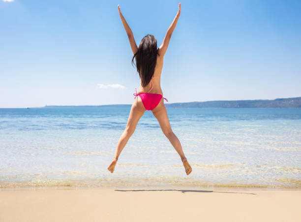 istock Happy young  woman jumping on beach 1003389870