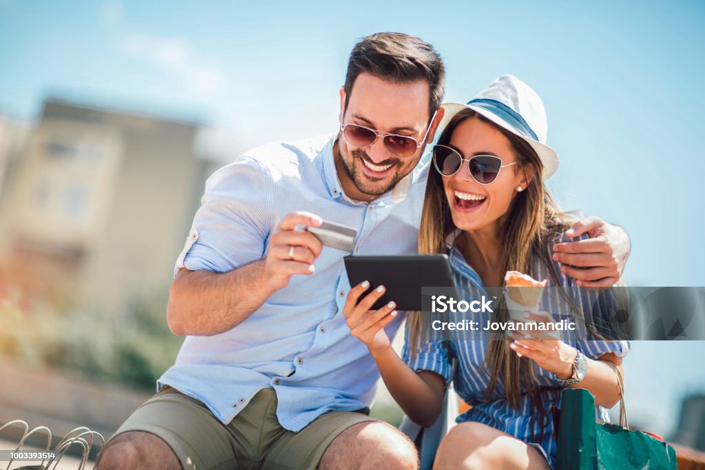 Pareja feliz pagando en línea con tarjeta de crédito y tableta digital en la calle - Foto de stock de Tarjeta de crédito libre de derechos
