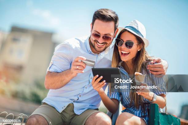 Happy Couple Paying On Line With Credit Card And Digital Tablet On The Street Stock Photo - Download Image Now