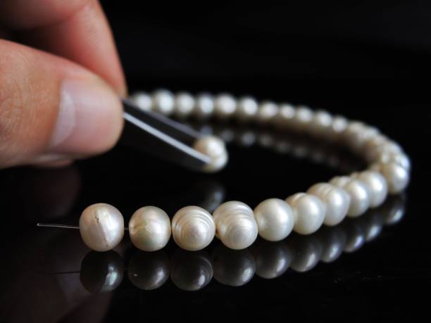 istock Cropped Hand Making Pearl Necklace Over Table 1003400228