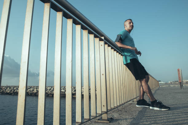 istock Confident male jogger resting leaning on bridge 1003402998